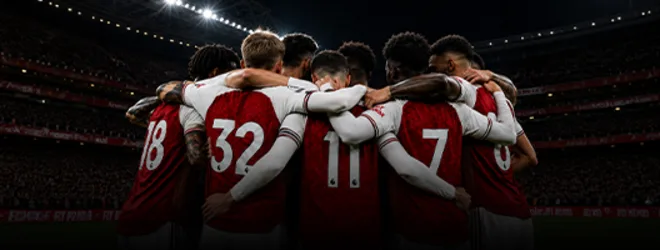 Fotografía publicitaria de futbolistas de un club europeo formando un círculo de espaldas en un estadio iluminado de noche.
